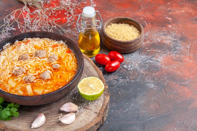 Oben Blick auf köstliche Nudelsuppe mit Hühnchen auf Holz-Tary Greens Ölflasche Knoblauch-Tomaten-Zitrone auf dunklem Hintergrund