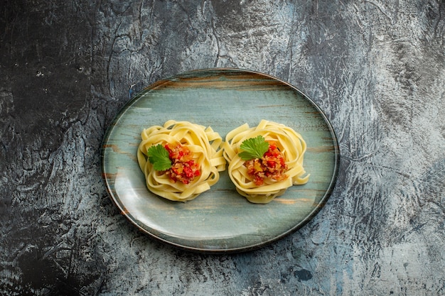 Kostenloses Foto oben blick auf köstliche pasta-mahlzeit mit tomatenfleisch und grün auf einem blauen teller auf eishintergrund