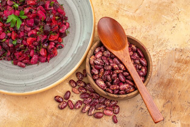 Oben Blick auf köstlichen Salat mit roter Beete und Bohnen und Bohnen innerhalb und außerhalb des Topfes auf gemischtem Farbhintergrund