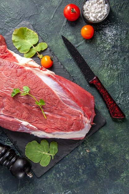 Oben Blick auf rohes frisches rotes Fleisch und Grüns auf Schneidebrettmessertomaten Holzhammer auf grün-schwarzem Mischfarbenhintergrund