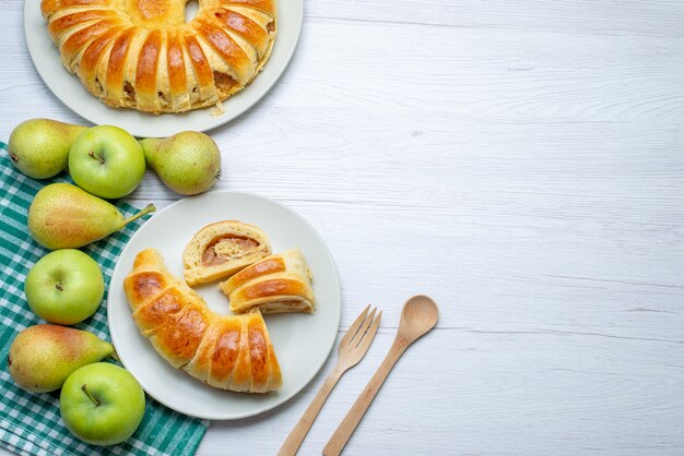 Oben entfernte Ansicht gebackene köstliche Gebäckarmreif gebildet innerhalb Glasplatte zusammen mit Äpfeln und Birnen auf weißem Schreibtisch, Gebäckkeks süß