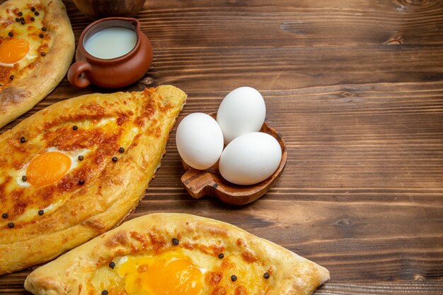 Oben Nahansicht gebackene Eierbrote frisch aus dem Ofen auf Holzoberfläche Teig Eierbrötchen Frühstücksbrot