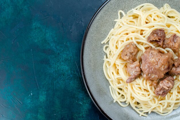 Oben Nahansicht gekochte italienische Nudeln mit geschnittenem Fleisch innerhalb Platte auf blauen Wand Nudeln Italien Essen Abendessen Teig Fleisch