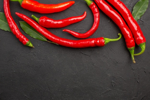 Oben Nahansicht rote Paprika und Pay-Blätter oben auf dem schwarzen Tisch mit freiem Platz