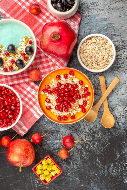 Oben Nahaufnahme Ansicht Beeren Schalen Haferflocken Beeren Äpfel Bonbons auf der karierten Tischdecke