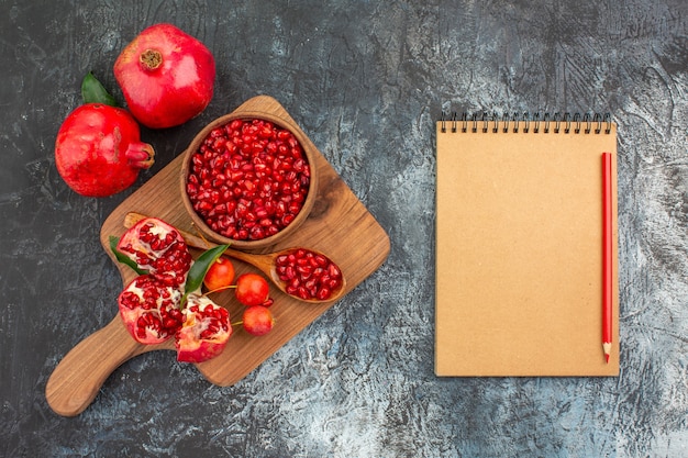 Oben Nahaufnahme Ansicht Früchte Notizbuch Bleistift das Brett mit Granatapfel Löffel Kirschen