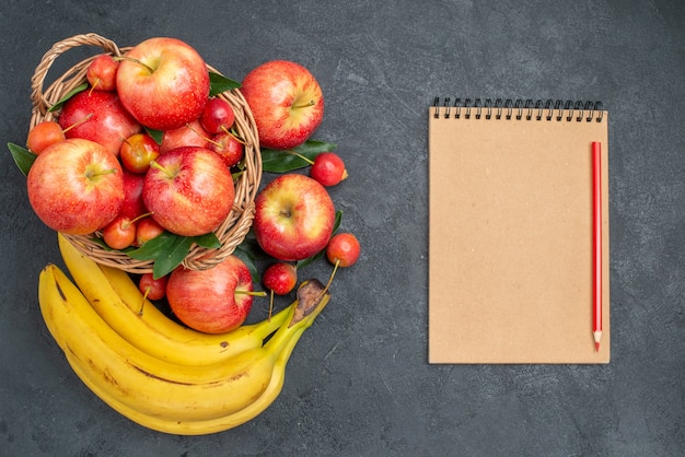 Oben Nahaufnahme Ansicht Obstkorb Kirschen Äpfel Bananen Notizbuch Bleistift