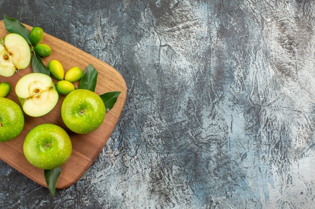 Oben Nahaufnahme Ansicht Äpfel grüne Äpfel Zitrusfrüchte mit Blättern auf dem Brett