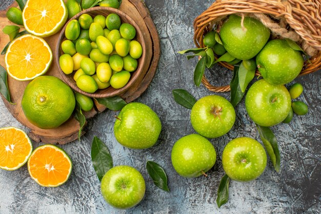 Oben Nahaufnahme Ansicht Äpfel Zitrusfrüchte auf dem Brett grüne Äpfel mit Blättern im Korb