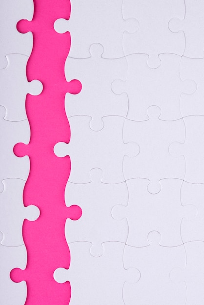 Oben sehen Sie weiße Puzzleteile und rosa Hintergrund