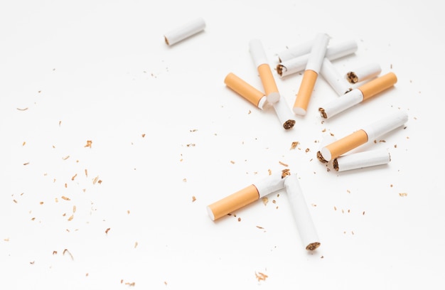 Obenliegende Ansicht der defekten Zigarette und des Tabaks gegen weißen Hintergrund