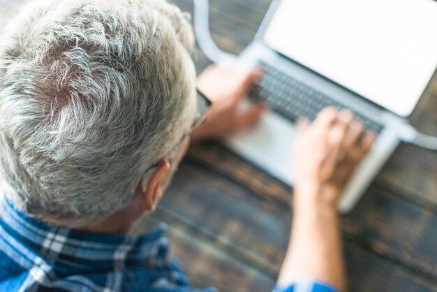 Obenliegende Ansicht des älteren Mannes, der Laptop verwendet