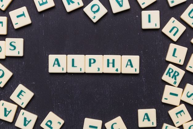 Obenliegende Ansicht des Alphatextes auf Scrabble-Buchstaben über schwarzem Hintergrund