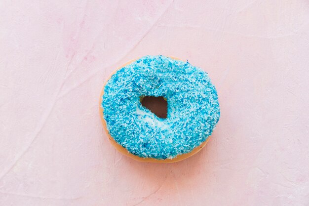 Obenliegende Ansicht des frischen blauen Donuts auf rosa Hintergrund