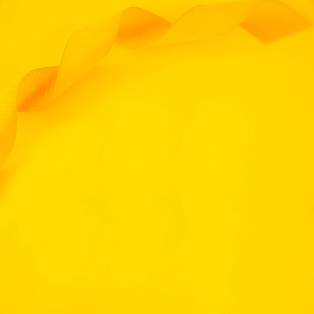 Obenliegende Ansicht des gekräuselten Satinbandes auf gelbem Hintergrund