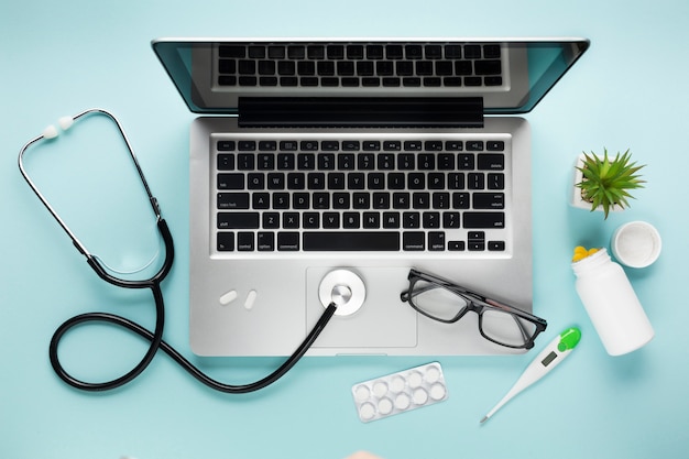 Obenliegende ansicht des gesundheitspflegeschreibtischs mit laptop und saftiger anlage