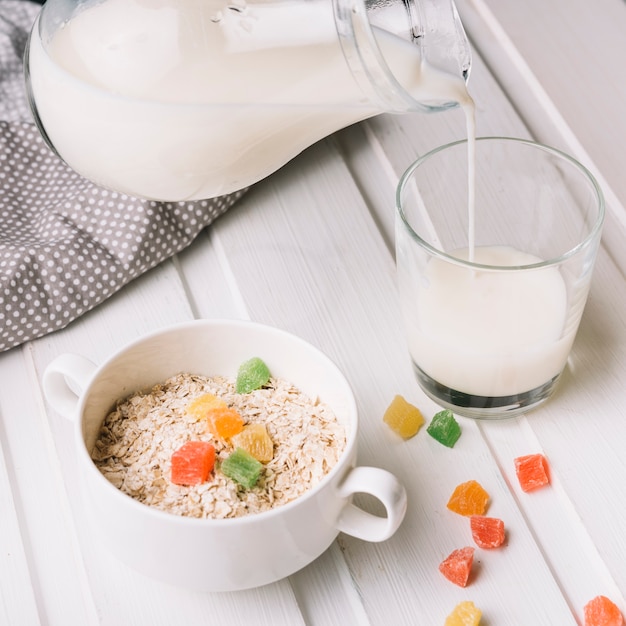 Obenliegende Ansicht des Hafermehls mit Glas auf Milch über der weißen Tabelle