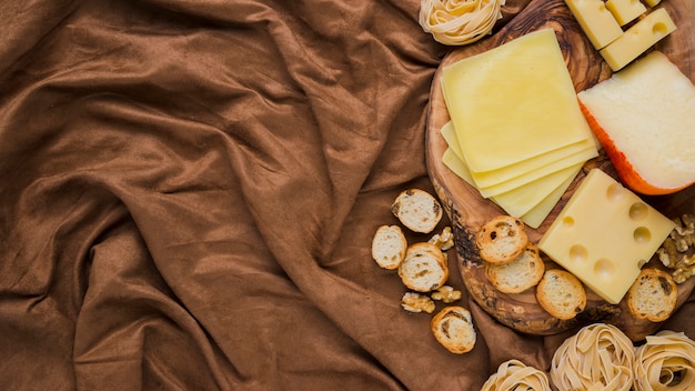 Obenliegende Ansicht des Käses, der Teigwaren und des Brotes auf zerquetschtem Gewebe