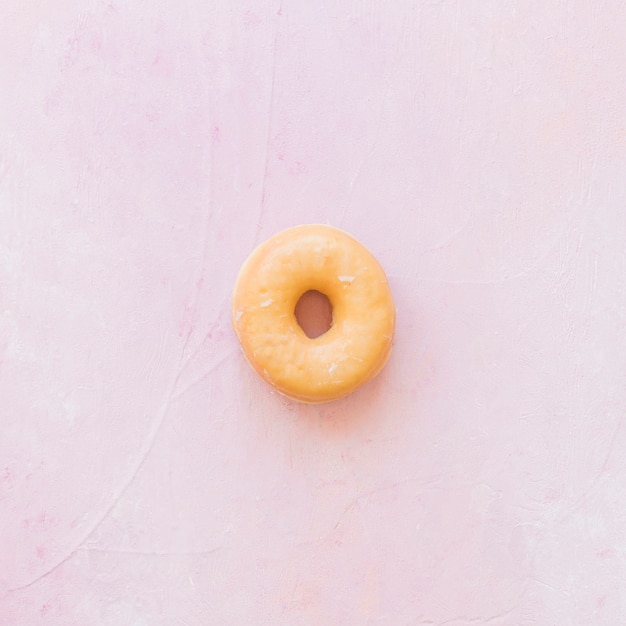 Obenliegende Ansicht des köstlichen glasig-glänzenden Donuts auf rosa Hintergrund