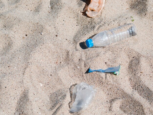 Obenliegende Ansicht des Plastikabfalls auf Sand am Strand