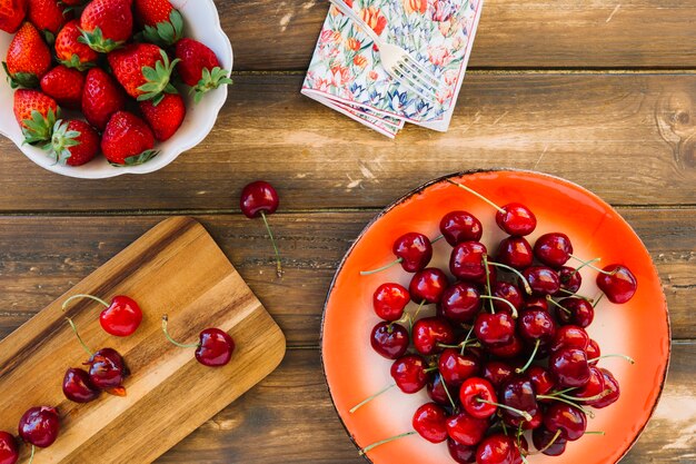 Obenliegende Ansicht von frischen roten Erdbeeren und von Kirschen auf hölzerner Planke