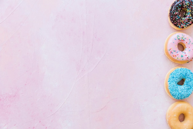 Obenliegende Ansicht von frischen Schaumgummiringen in Folge auf rosa Hintergrund