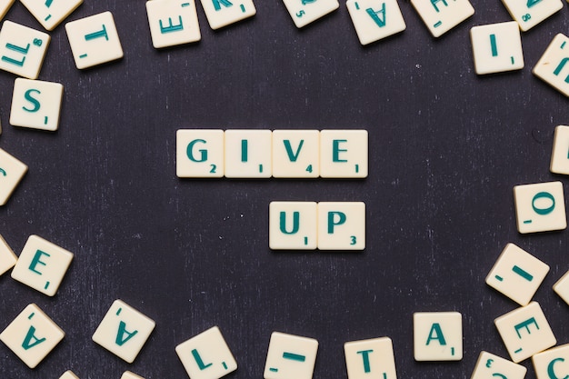 Kostenloses Foto obenliegende ansicht von geben text mit scrabble buchstaben gegen schwarzen hintergrund auf