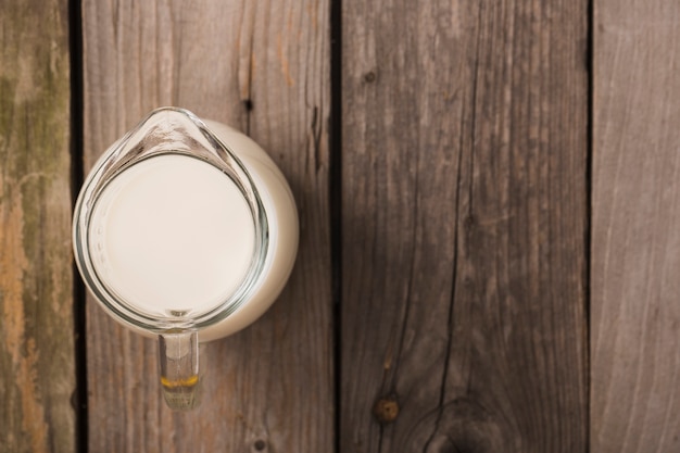 Obenliegende Ansicht von Milch im Krug auf dem Holztisch