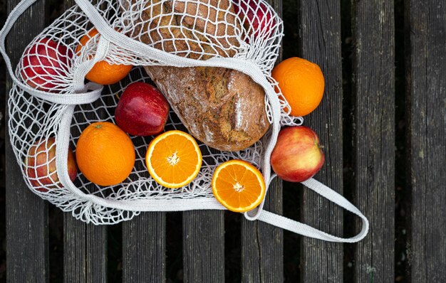 Obst und Brot in einer Einkaufstasche auf Holzhintergrund