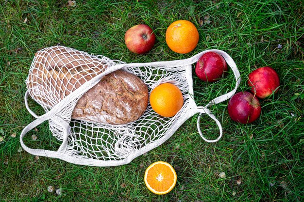 Obst und frisches Brot in einer Schnurtasche im Gras