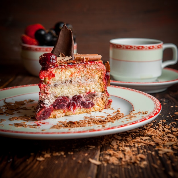 Obstkuchenstück mit Schokoladenstückchen und Tasse Tee und Blaubeeren in rundem Teller