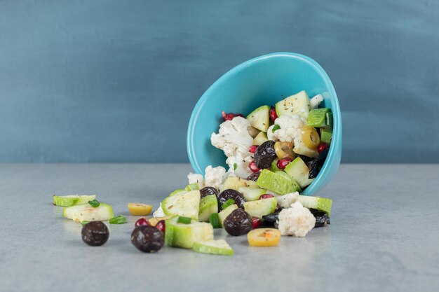 Obstsalat in einer blauen Tasse mit schwarzen Oliven.