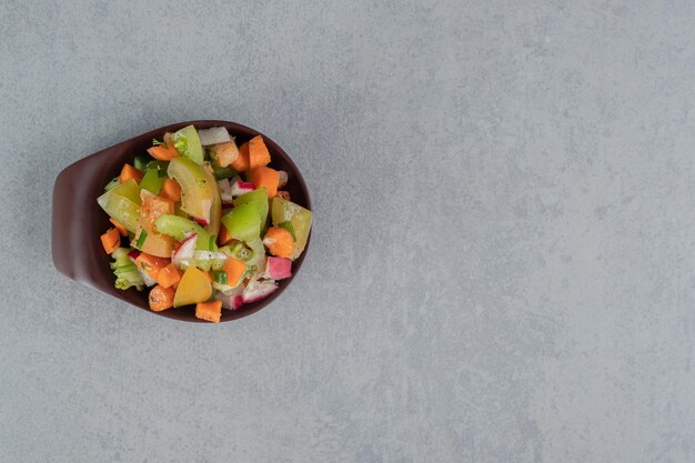 Obstsalat in einer braunen Tasse auf Betontisch.