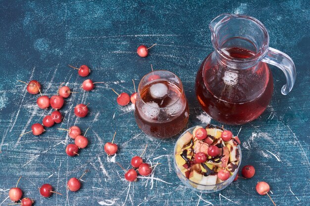 Obstsalat mit einem Glas rotem Saft auf blau.