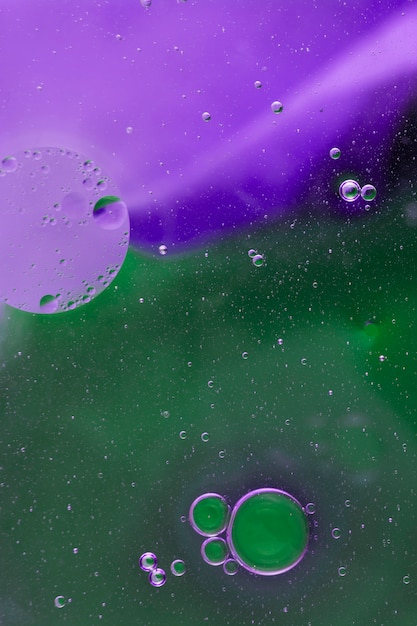 Kostenloses Foto Ölblasen, die auf grünen und purpurroten aquarellhintergrund schwimmen