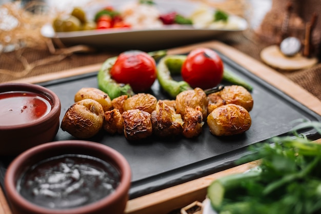 Kostenloses Foto ofenkartoffel auf holzbrett mit pfeffer tomatensaucen seitenansicht