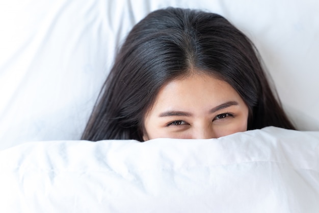 Offene augen des schönen jugendlichen bedeckt ihr gesicht mit decke