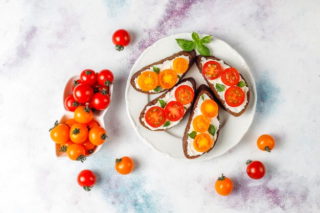 Offene Sandwiches mit Hüttenkäse, Kirschtomaten und Basilikum.