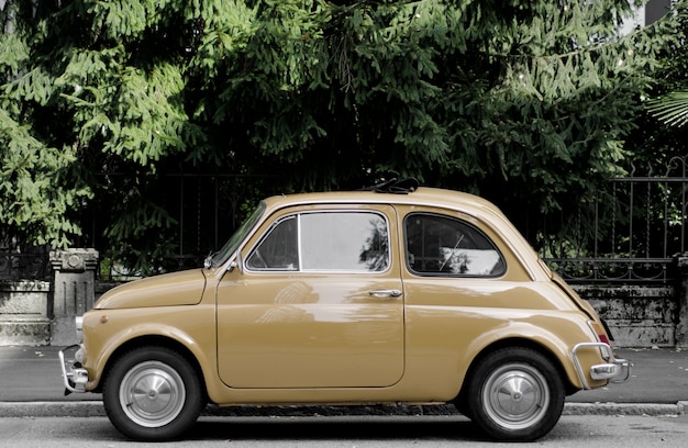 Kostenloses Foto oldtimer auf der straße, umgeben von bäumen unter dem sonnenlicht