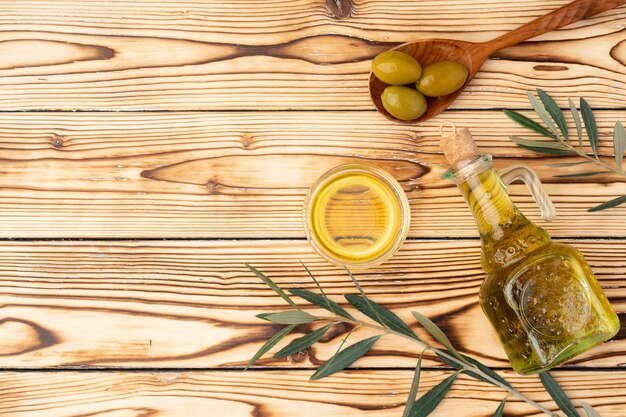 Oliven und eine Flasche Olivenöl auf Holzuntergrund