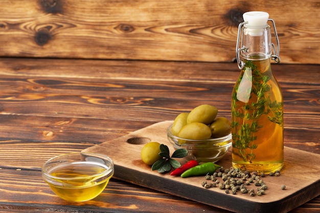 Oliven und eine Flasche Olivenöl auf Holzuntergrund