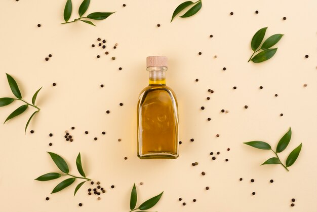 Olivenölflasche umgeben von Olivenblättern