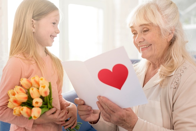 Oma mit Blumen und Grußkarte vom Mädchen