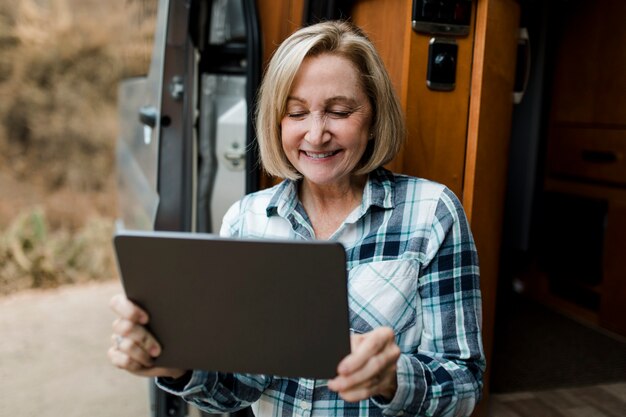 Oma sitzt im Wohnmobil und schaut auf sein Tablet