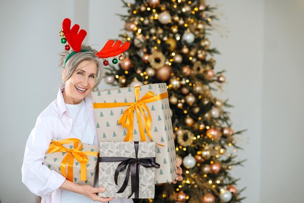 Oma trägt Hirschweihnachtsmütze Weihnachtsgeschenke in Händen
