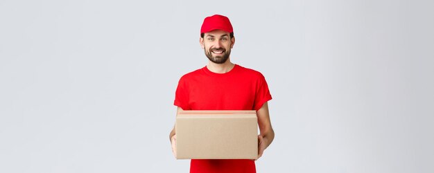 Online-Shopping- und Paketversandkonzept für die Lieferung der Bestellung Lächelnder, freundlicher Kurier bringt das Paket vor die Haustür des Kunden Mitarbeiter in roter Servicekappe und T-Shirt, das das Paket für den Kunden hält