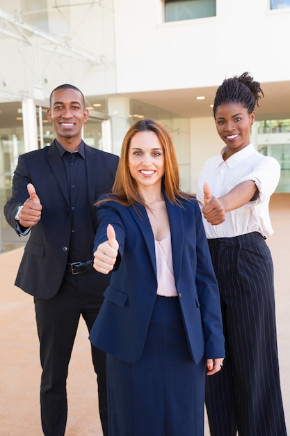 Optimistische junge zwischen verschiedenen Rassen Geschäftsleute, die Thumbs-up zeigen