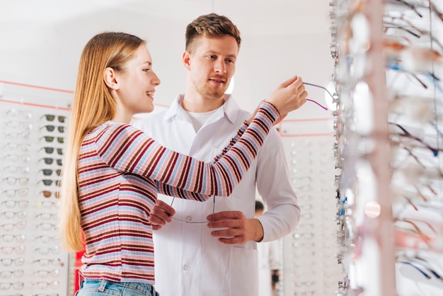 Optometriker, der die Frau wählt Gläser berät