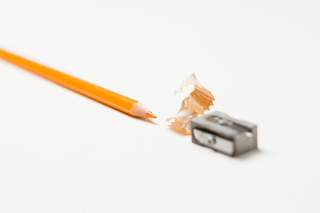 Orange Bleistift und Bleistiftspitzer auf weißem Hintergrund
