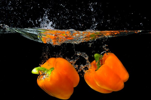 Orange Pfeffer mit zwei Orangen, der unter das Wasser schwimmt